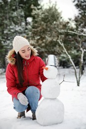 Young woman making snowman outdoors on winter day