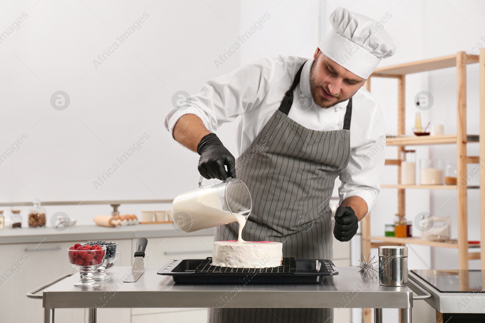 Photo of Male pastry chef preparing cake at table in kitchen