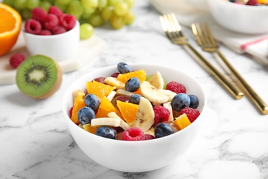 Photo of Fresh tasty fruit salad on white marble table