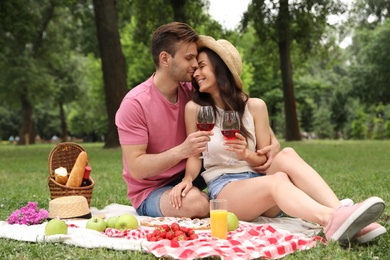 Photo of Happy young couple having picnic in park on summer day