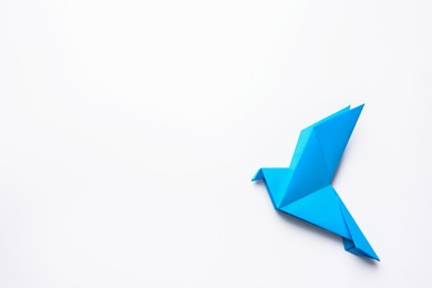 Photo of Beautiful blue origami bird on white background, top view. Space for text