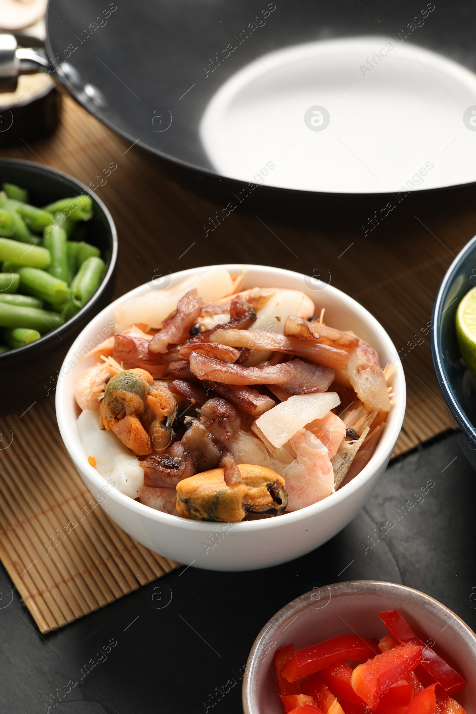 Photo of Black wok and products on dark table, closeup