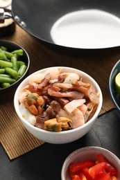 Black wok and products on dark table, closeup