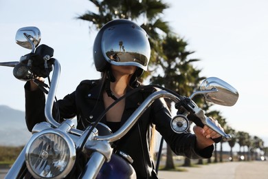 Photo of Woman in helmet riding motorcycle on sunny day