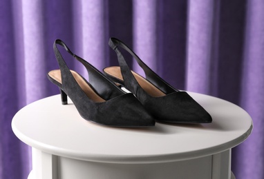 Pair of female shoes on table against curtain