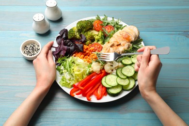 Photo of Balanced diet and healthy foods. Woman eating dinner at light blue wooden table, above view