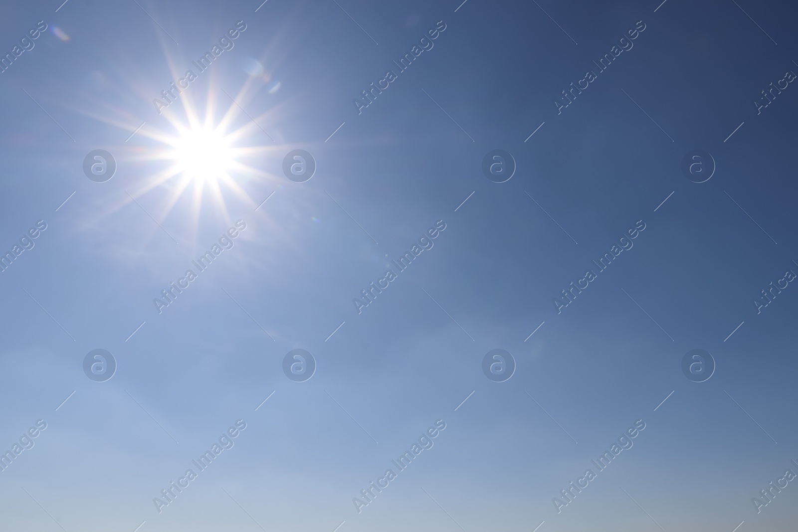 Photo of Bright sun in blue sky. Halo effect