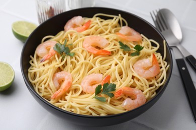 Photo of Tasty spaghetti with shrimps and parsley in bowl on light tiled table, closeup