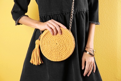 Photo of Young woman in stylish outfit with purse on color background, closeup