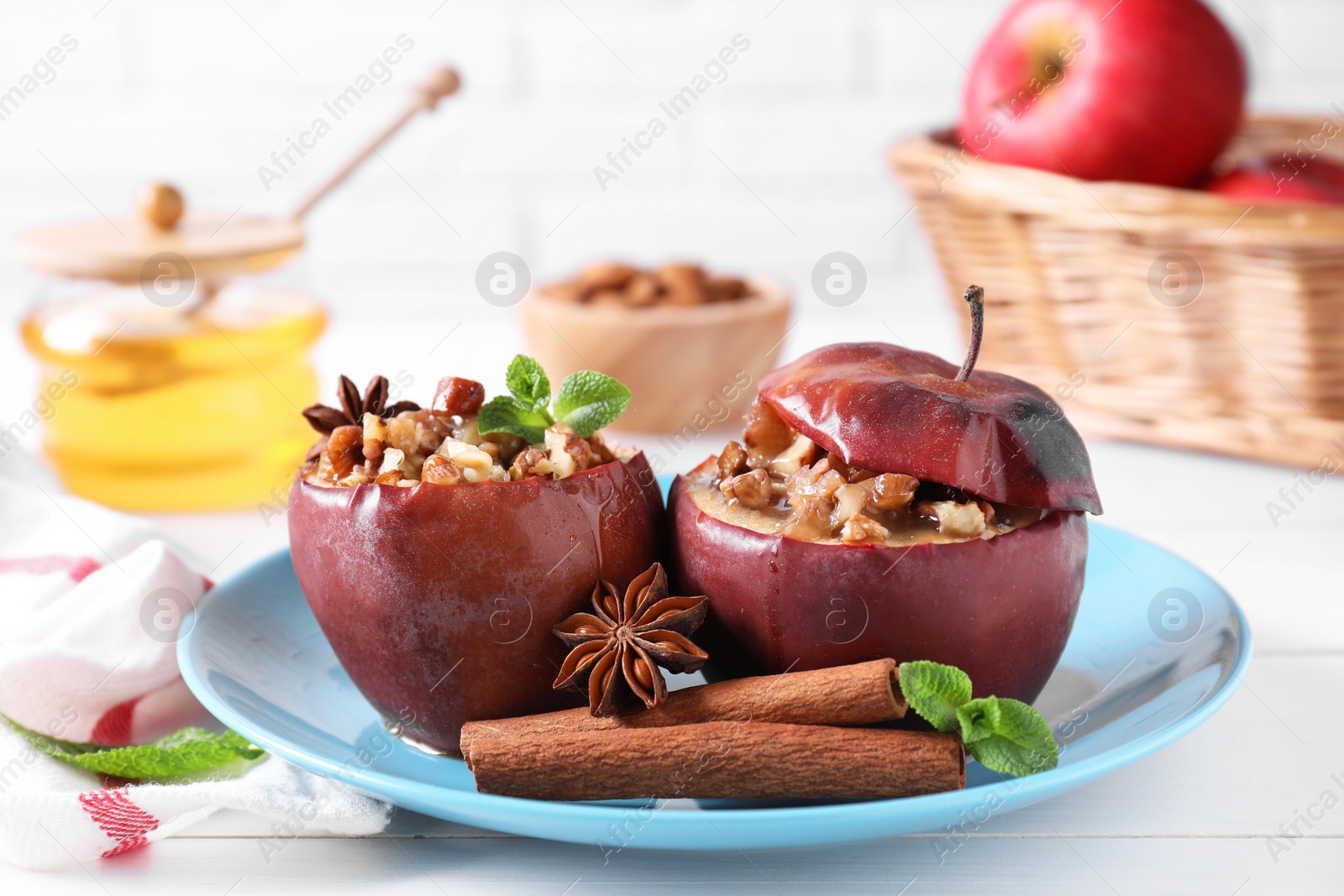 Photo of Tasty baked apples with nuts, honey, spices and mint on white wooden table