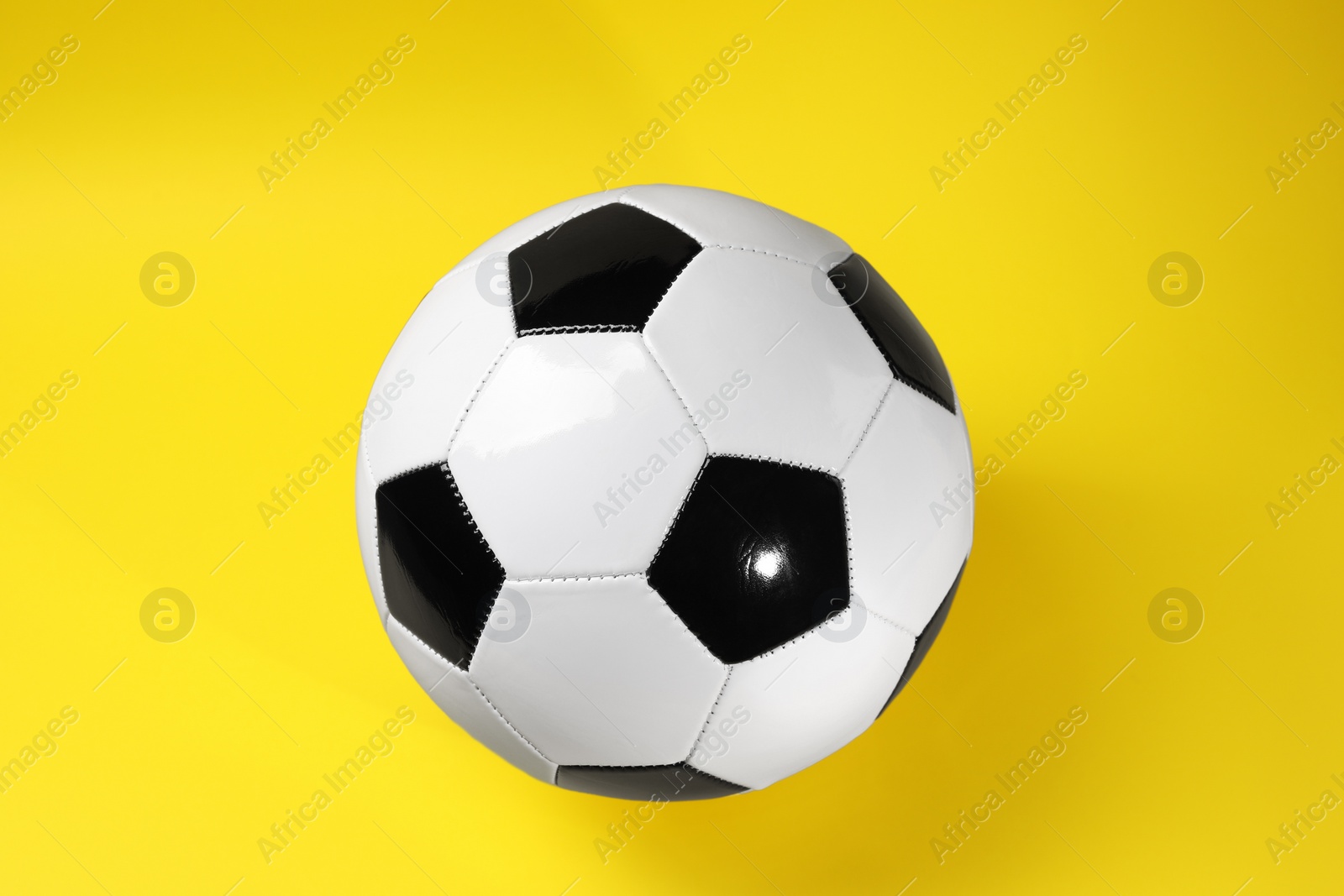 Photo of One soccer ball on yellow background, top view. Sports equipment
