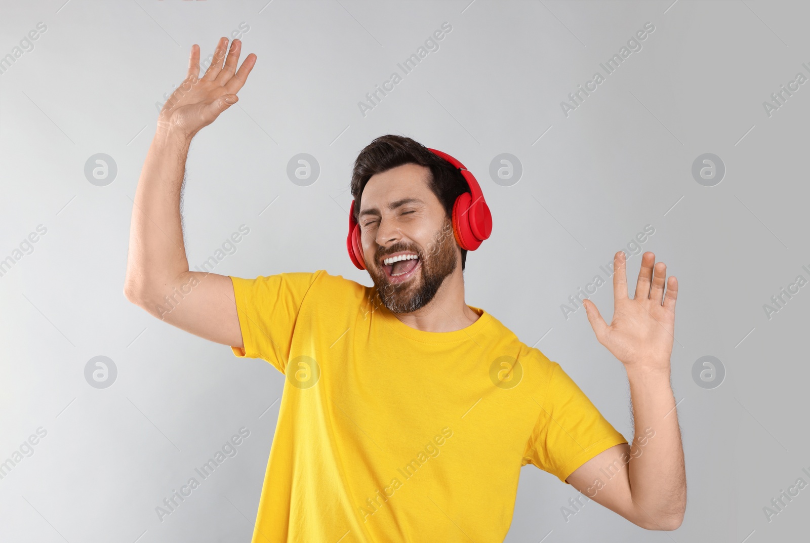 Photo of Emotional man listening music with headphones on light grey background
