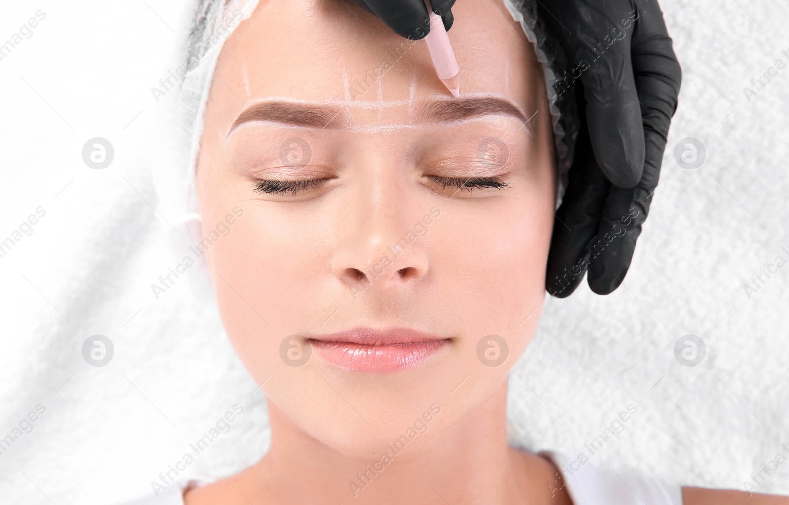 Photo of Young woman undergoing eyebrow correction procedure in salon, top view