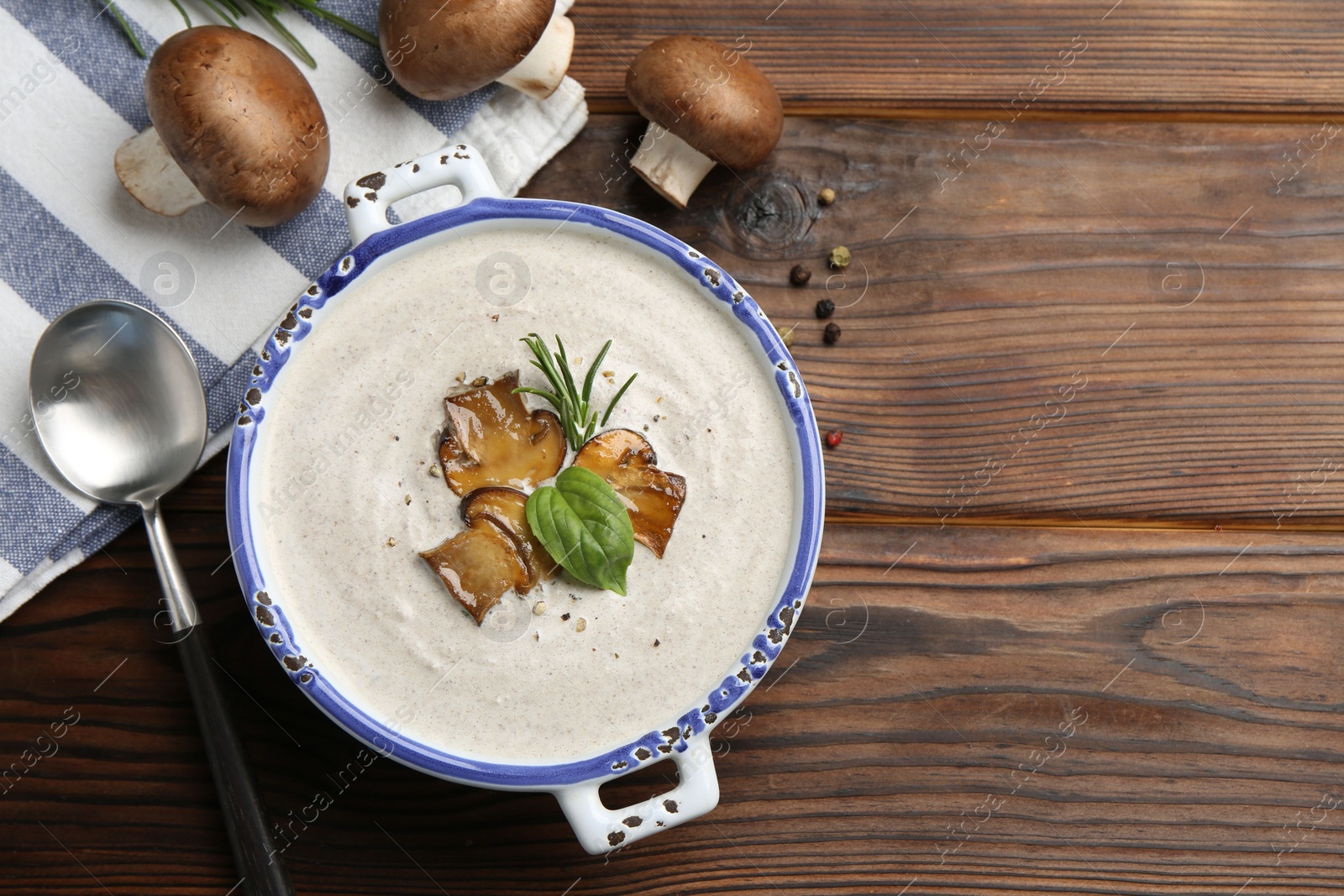 Photo of Delicious homemade mushroom soup served on wooden table, flat lay. Space for text