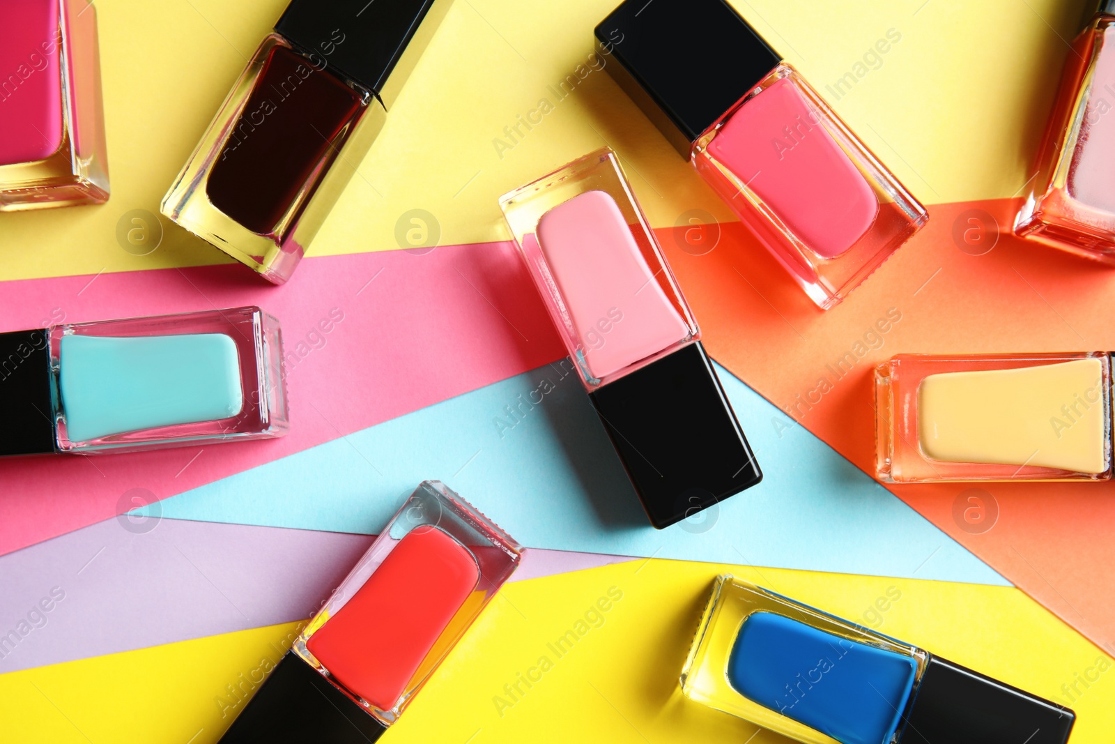 Photo of Bottles of nail polish on color background, top view