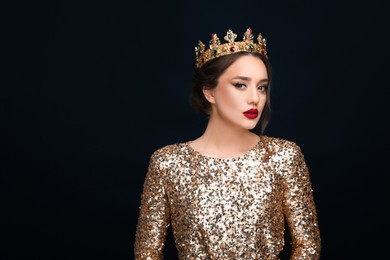 Photo of Beautiful young woman wearing luxurious crown on black background, space for text