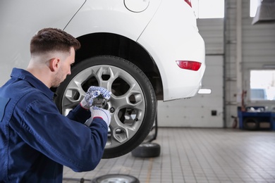 Photo of Young mechanic changing wheel at tire service