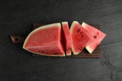 Photo of Slices of ripe juicy watermelon on black table, top view