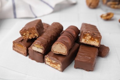 Photo of Pieces of different tasty chocolate bars on white table, closeup