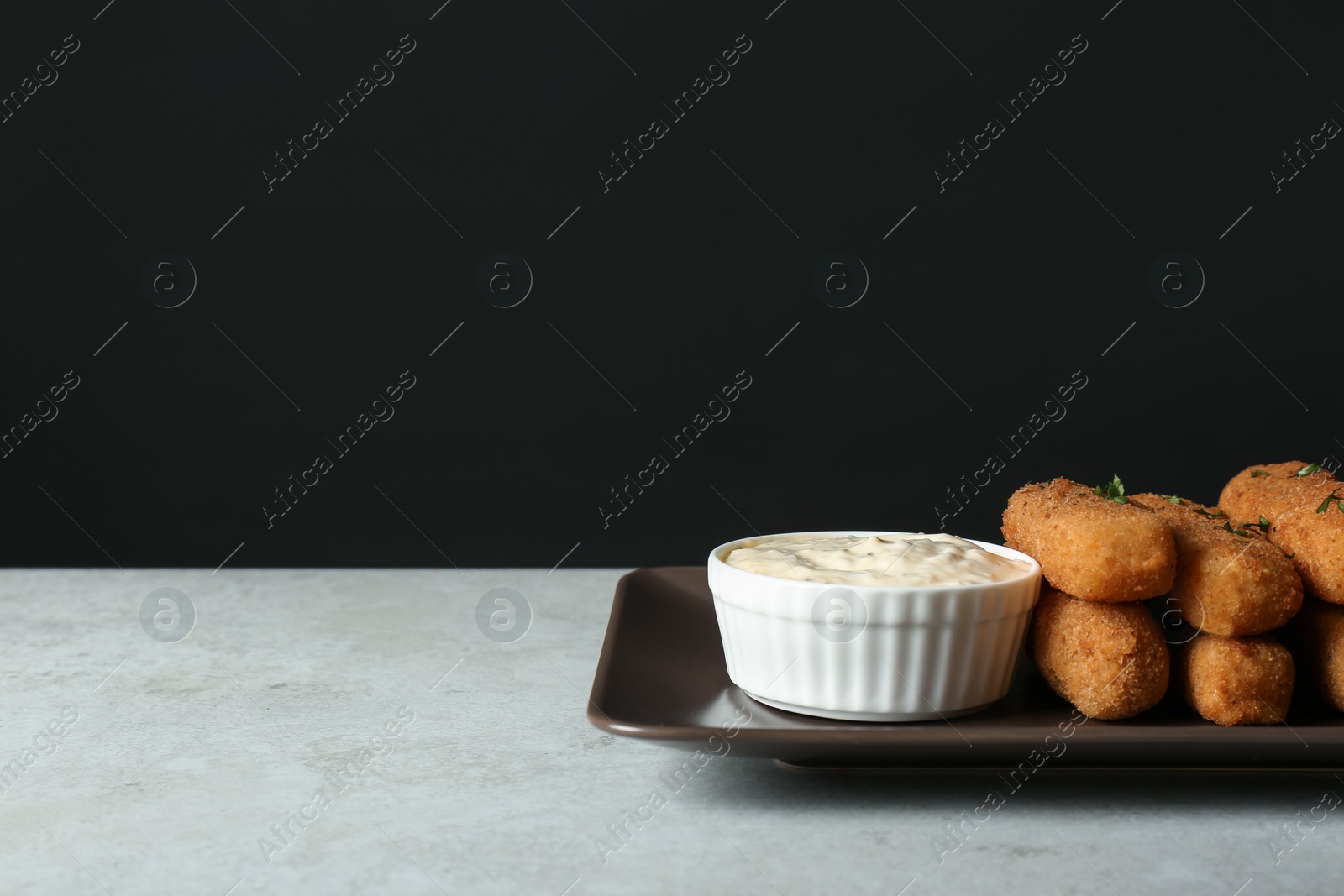 Photo of Plate with cheese sticks and sauce on table. Space for text