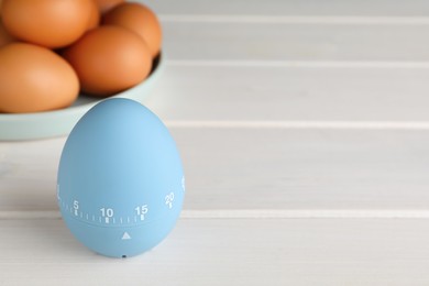 Kitchen timer and eggs on white wooden table. Space for text