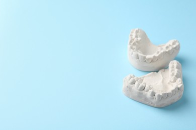 Photo of Dental model with gums on light blue background, space for text. Cast of teeth