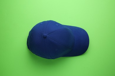 Stylish blue baseball cap on light green background, top view