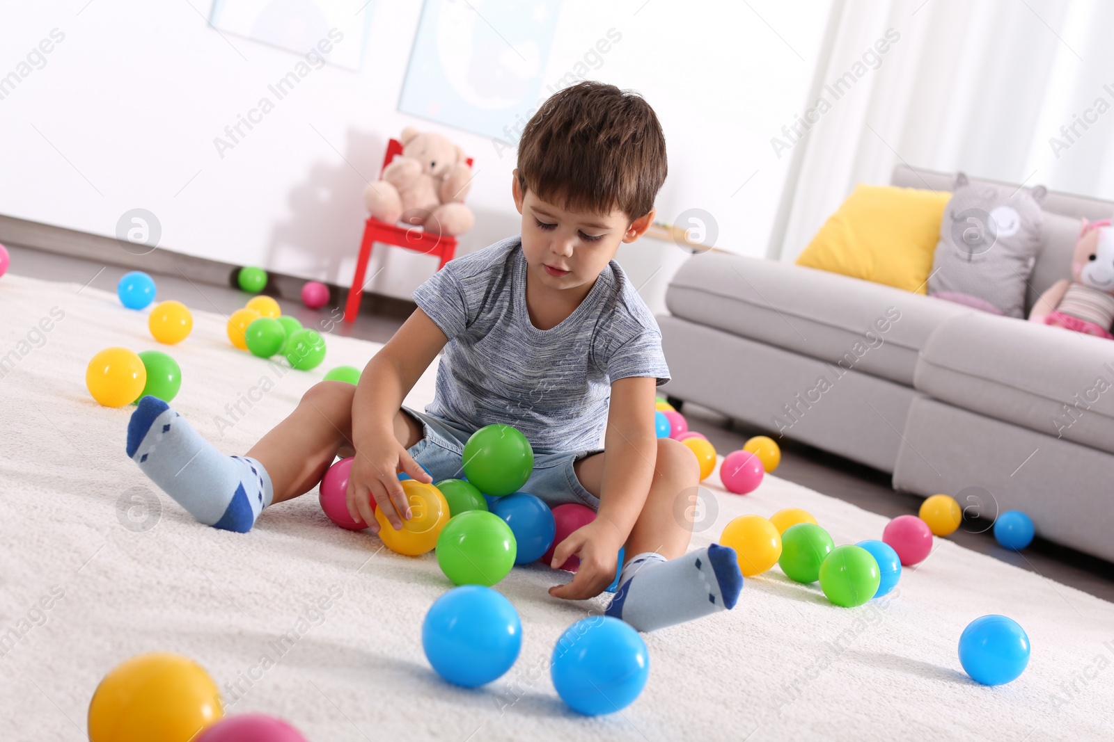 Photo of Cute little boy playing with toys on floor at home