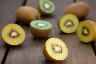 Photo of Many whole and cut fresh kiwis on wooden table, closeup