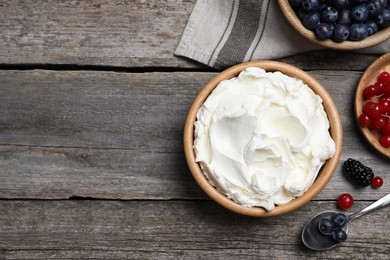 Tasty cream cheese and fresh berries on wooden table, flat lay. Space for text