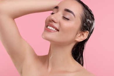 Photo of Portrait of beautiful happy woman washing hair on pink background