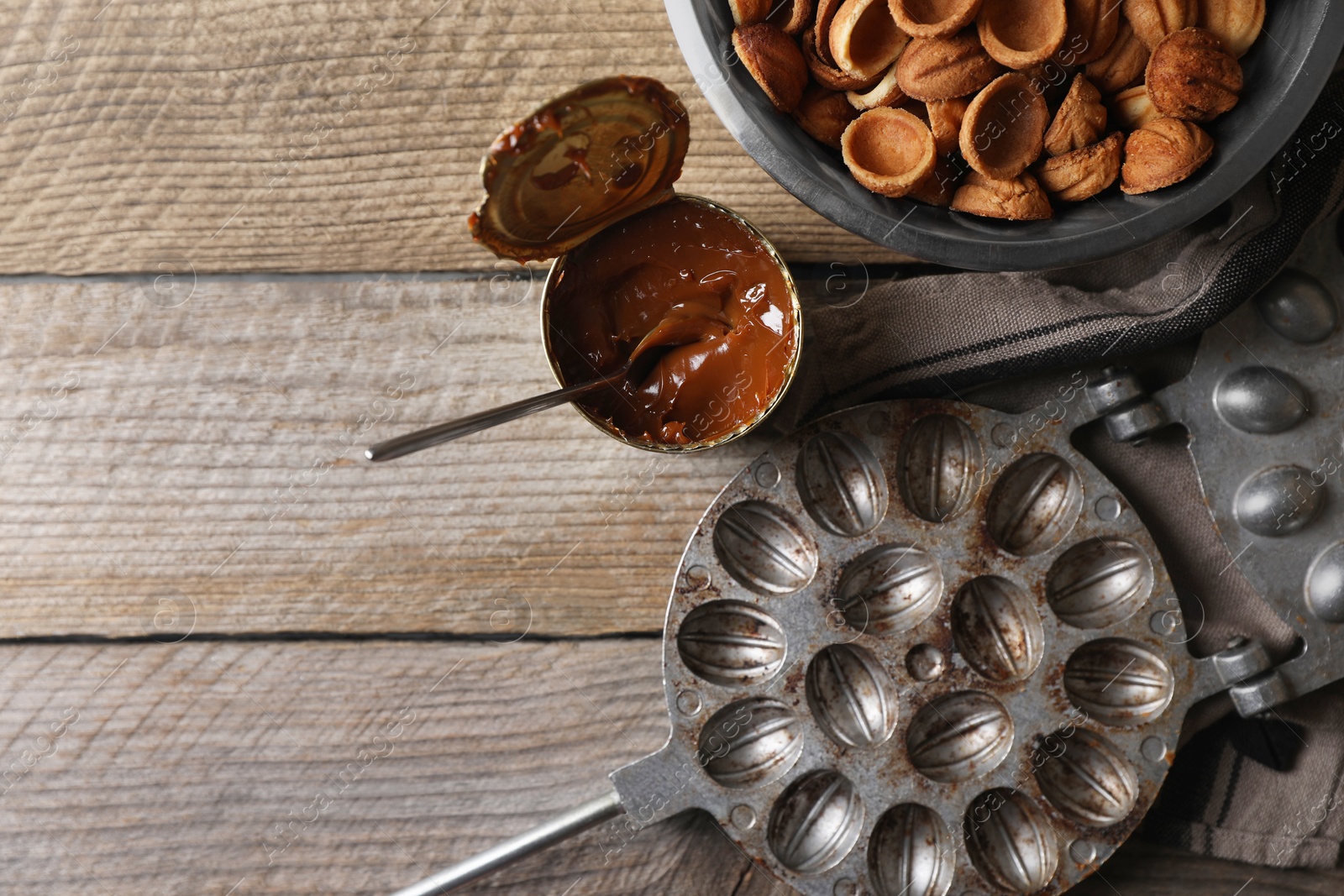 Photo of Making walnut shaped cookies. Cooked dough, caramelized condensed milk and mold on wooden table, flat lay. Space for text