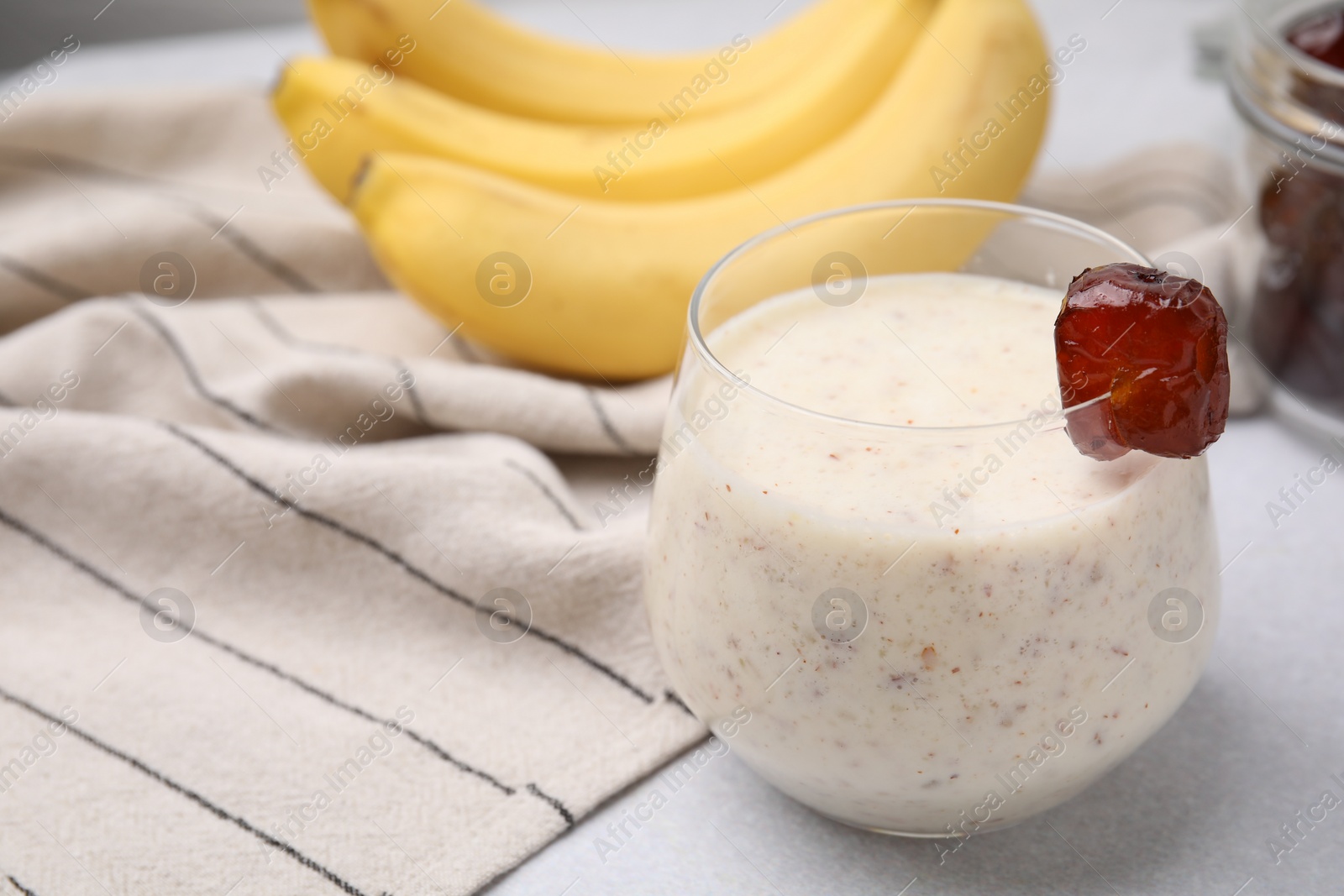 Photo of Glass of delicious date smoothie on white table, closeup. Space for text