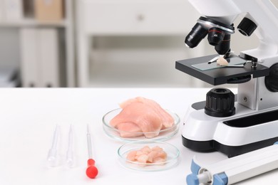 Photo of Food quality control. Microscope, petri dishes with meat and other laboratory equipment on white table