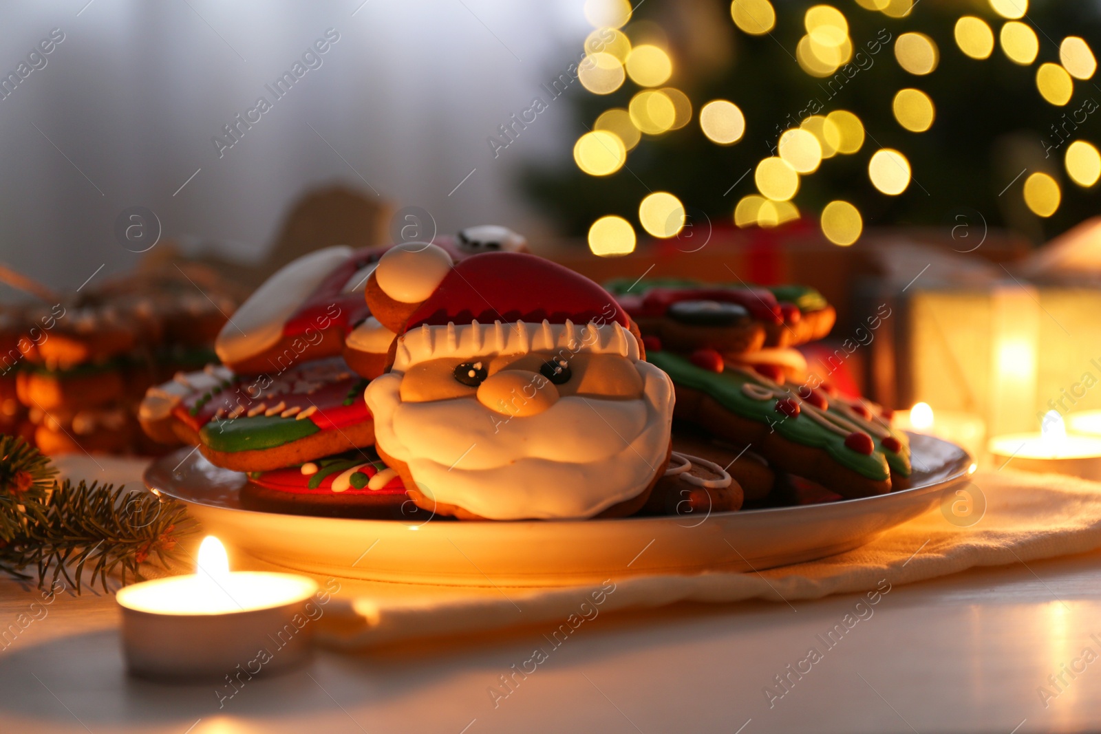 Photo of Decorated cookies on white table against blurred Christmas lights