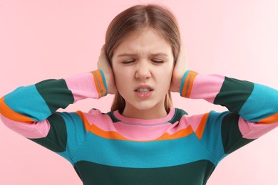 Photo of Hearing problem. Little girl suffering from ear pain on pink background