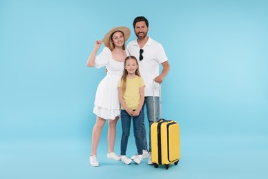 Happy family with yellow suitcase on light blue background