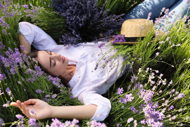 Photo of Young woman lying in lavender field on summer day