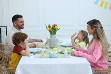 Cute family celebrating Easter at served table in room