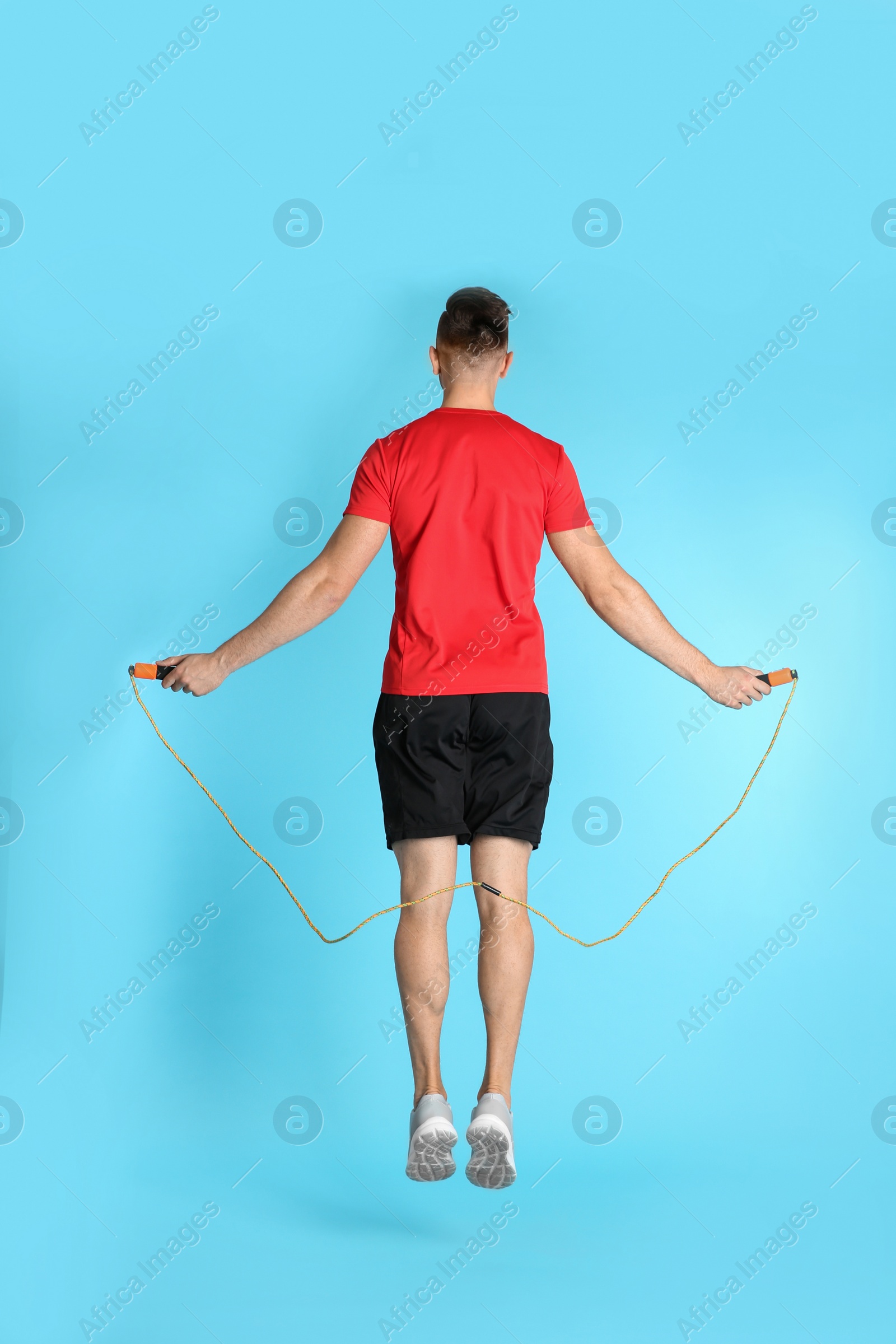 Photo of Sportive man training with jump rope on color background