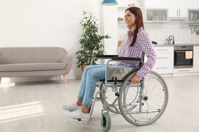 Photo of Young woman sitting in modern wheelchair indoors