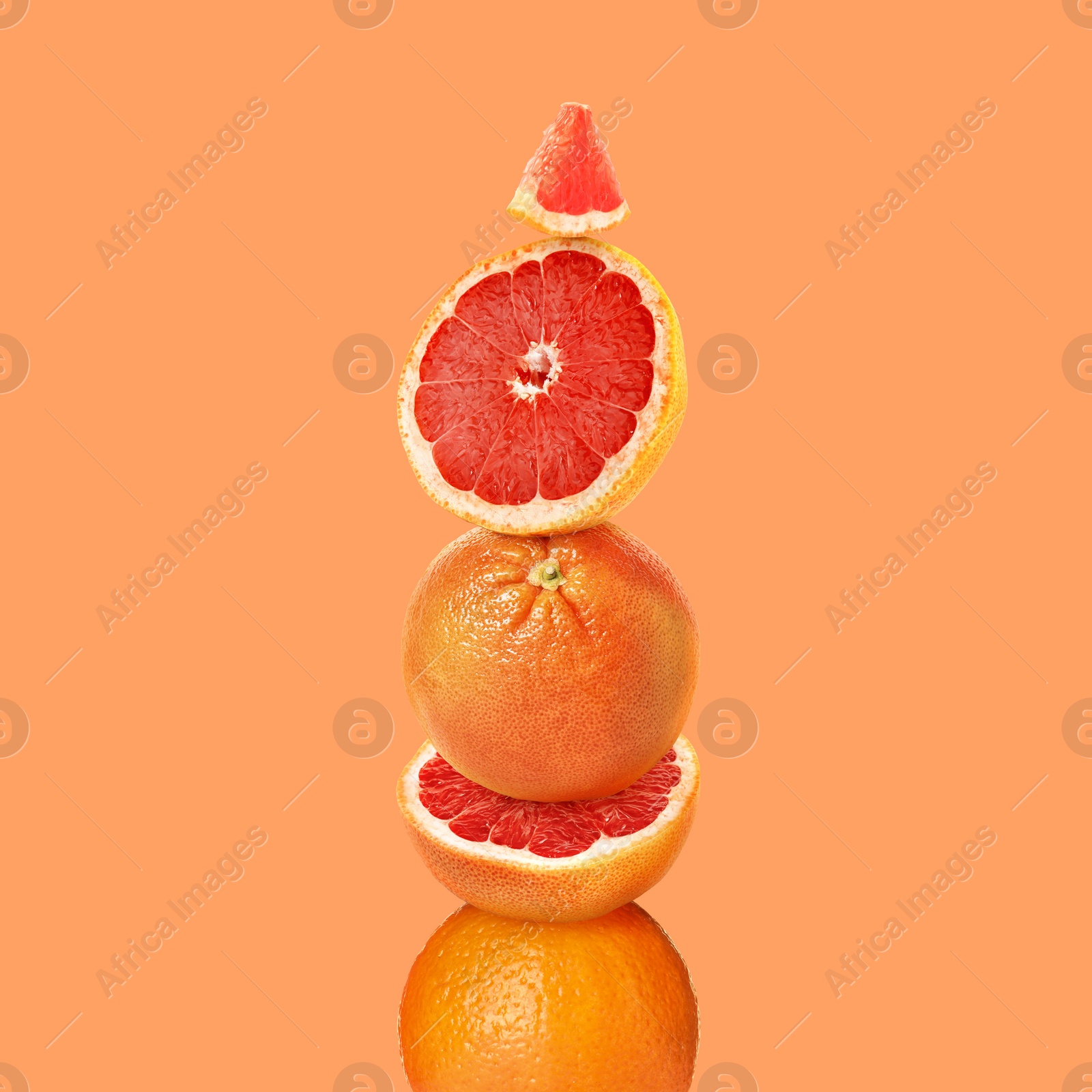 Image of Stacked cut and whole grapefruits on orange background