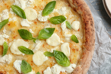 Delicious hot cheese pizza with basil on table, top view