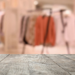 Image of Empty wooden table and blurred view of store with modern clothes