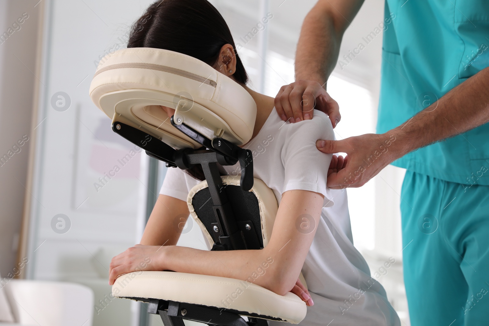 Photo of Woman receiving massage in modern chair indoors