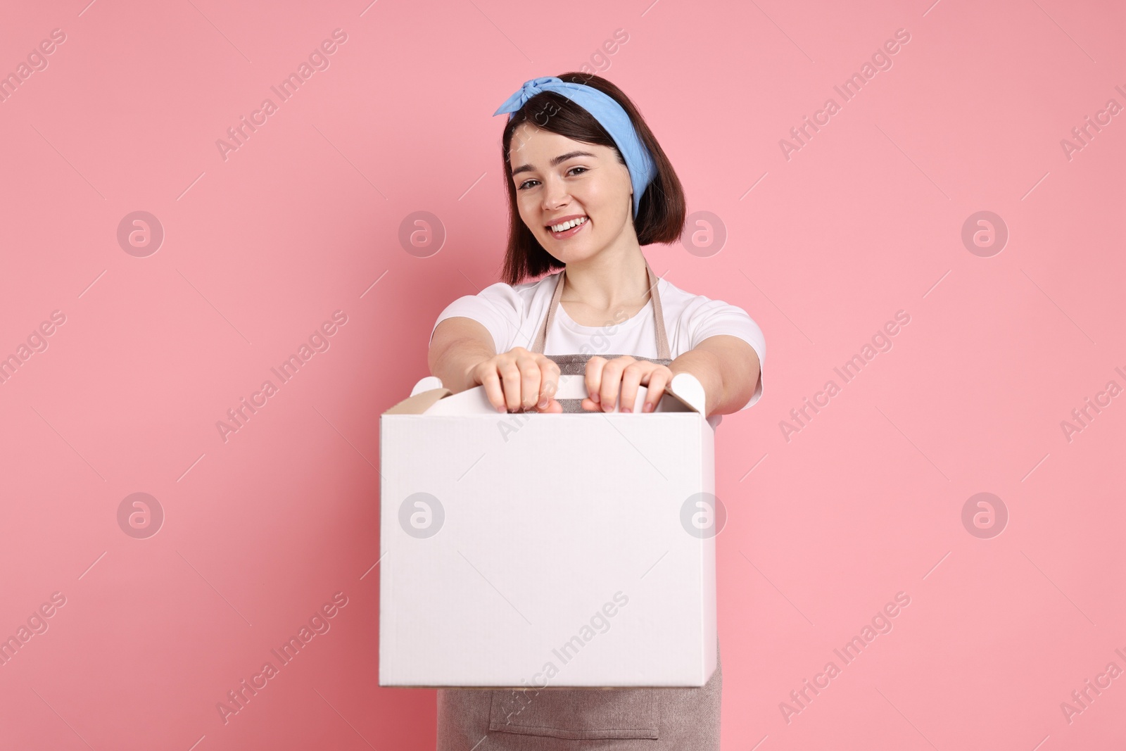 Photo of Happy confectioner with cake box on pink background