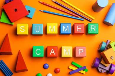 Photo of Colorful wooden cubes with phrase SUMMER CAMP on orange background, flat lay