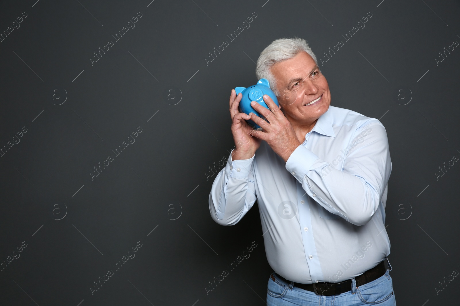 Photo of Mature man with piggy bank on grey background. Space for text