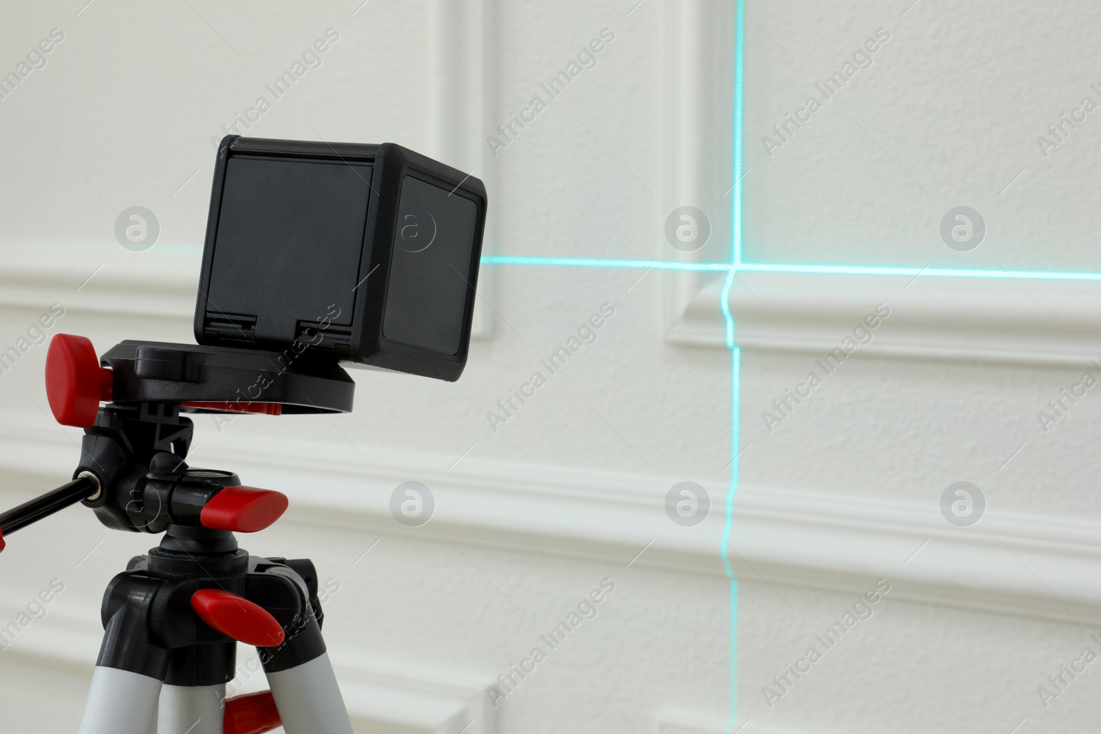 Photo of Cross line laser level on tripod in front of white wall