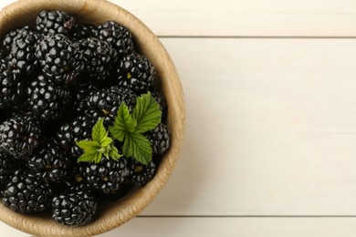 Bowl with fresh ripe blackberries on white wooden table, top view. Space for text